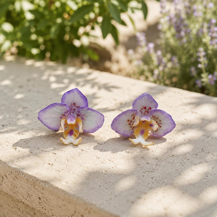 Purple orchid flower stud earrings with garnet stone chip accents on outdoor stone surface