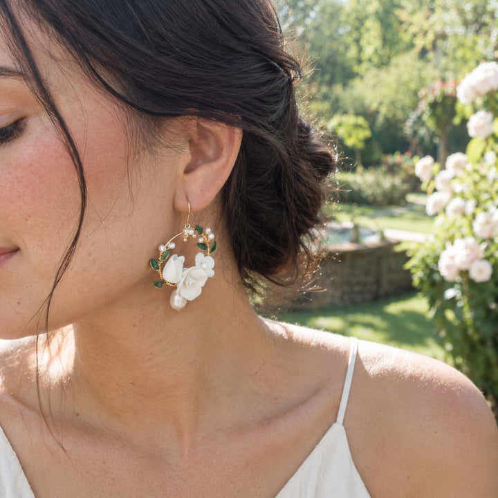 Woman wearing handcrafted porcelain floral hoop earrings in natural sunlight