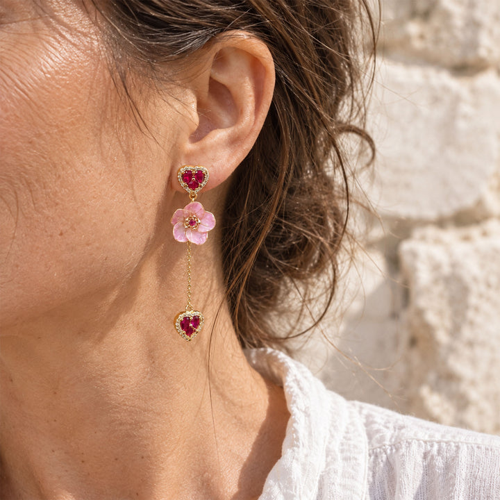 Pink sakura flower and heart CZ drop earrings arranged on a white marble surface in direct sunlight.