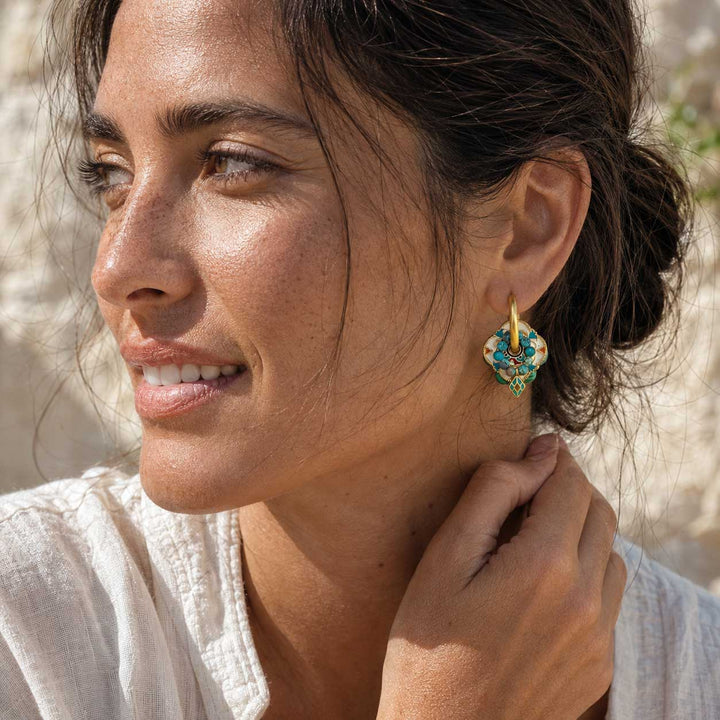 Model wearing convertible hoop earrings with malachite, African turquoise and hand-painted enamel in natural sunlight.