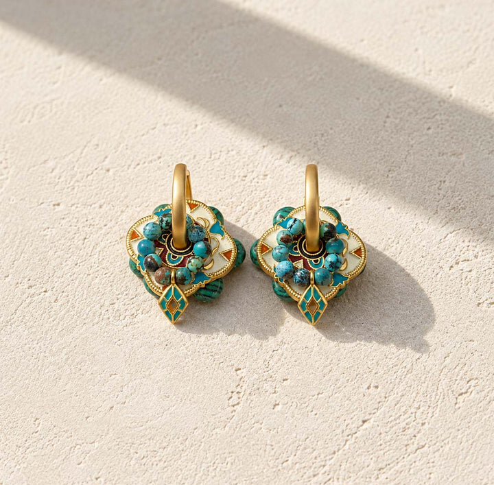 Convertible hoop earrings featuring malachite, African turquoise and hand-painted enamel styled as statement earrings on a stone surface.