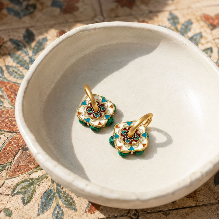 Convertible hoop earrings with malachite and hand-painted enamel displayed in a ceramic bowl.