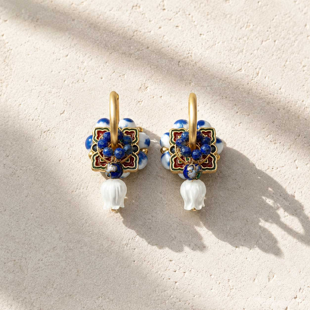 Complete interchangeable Blue Porcelain Convertible Hoop Earrings set with porcelain bead hoops, cloisonné enamel medallions, lapis bead rings, lapis drop charms and hand-carved mother of pearl tulip charms, photographed on a light textured surface with soft shadows.