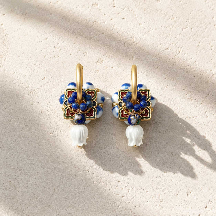 Complete interchangeable Blue Porcelain Convertible Hoop Earrings set with porcelain bead hoops, cloisonné enamel medallions, lapis bead rings, lapis drop charms and hand-carved mother of pearl tulip charms, photographed on a light textured surface with soft shadows.