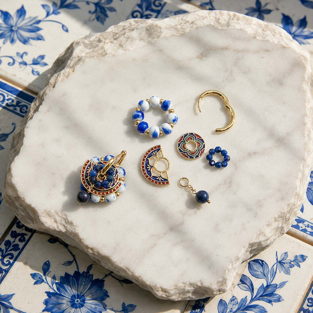 Blue porcelain convertible hoop earrings with hand-painted enamel medallions and porcelain bead hoops on a natural stone surface.