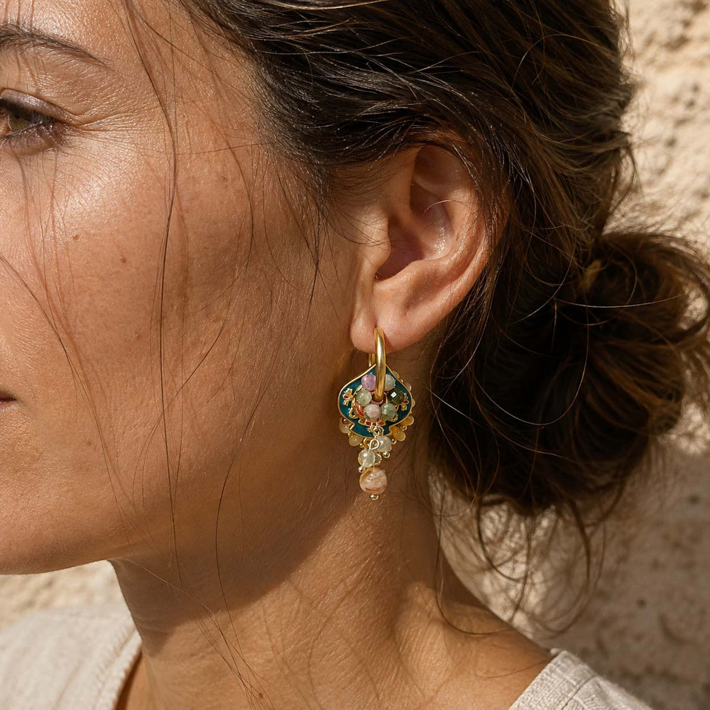 A close-up of a woman's ear wearing a convertible enamel hoop earrings with multicolor tourmaline and citrine drops
