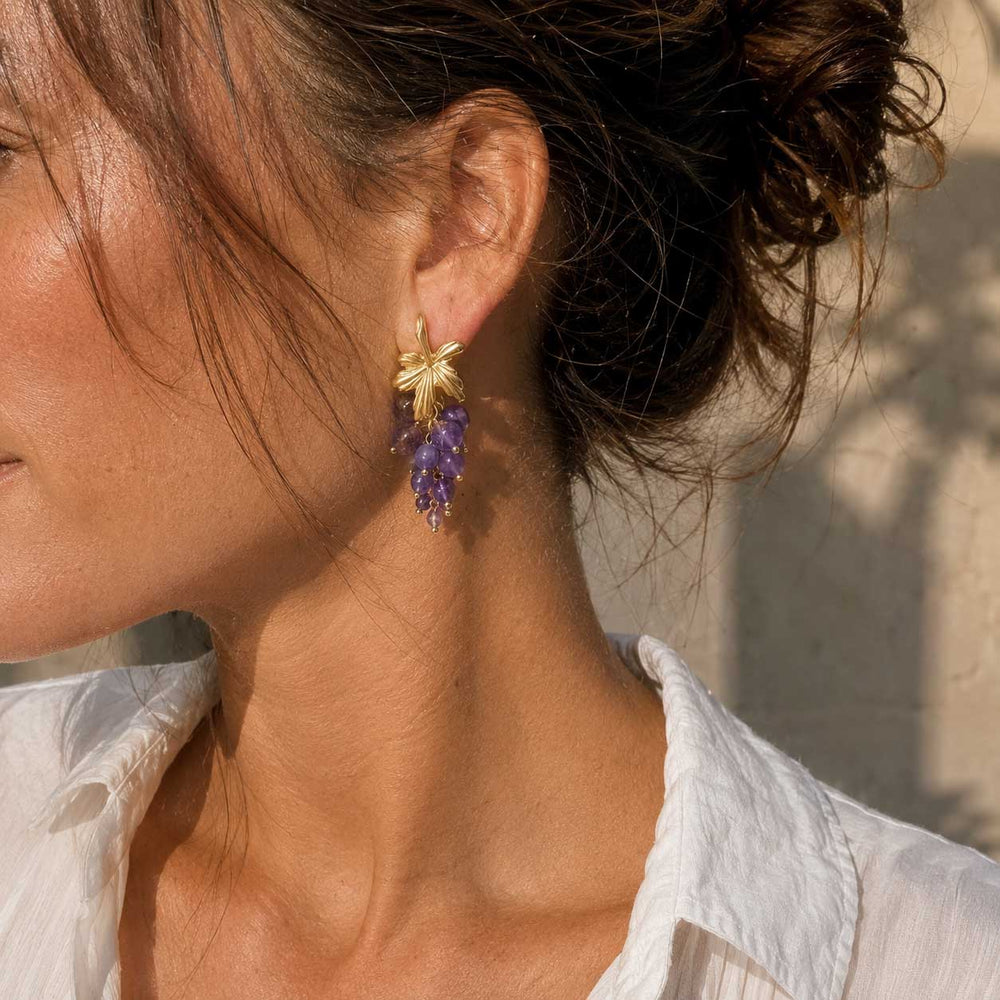 Model wearing A2K London handcrafted amethyst grape cluster earrings in natural sunlight.