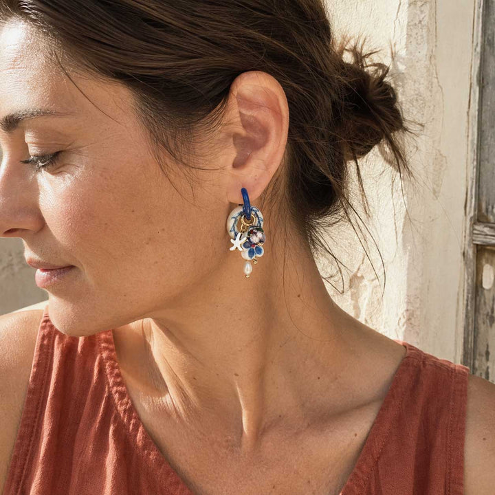 A model wearing handcrafted blue and white porcelain convertible charm hoop earrings by A2K.