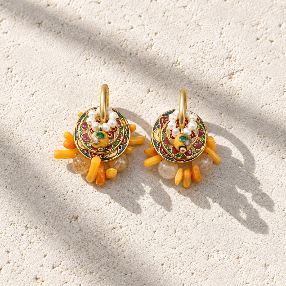Convertible hoop earrings with natural citrine, coral, cloisonné and freshwater pearl components on a marble slab.