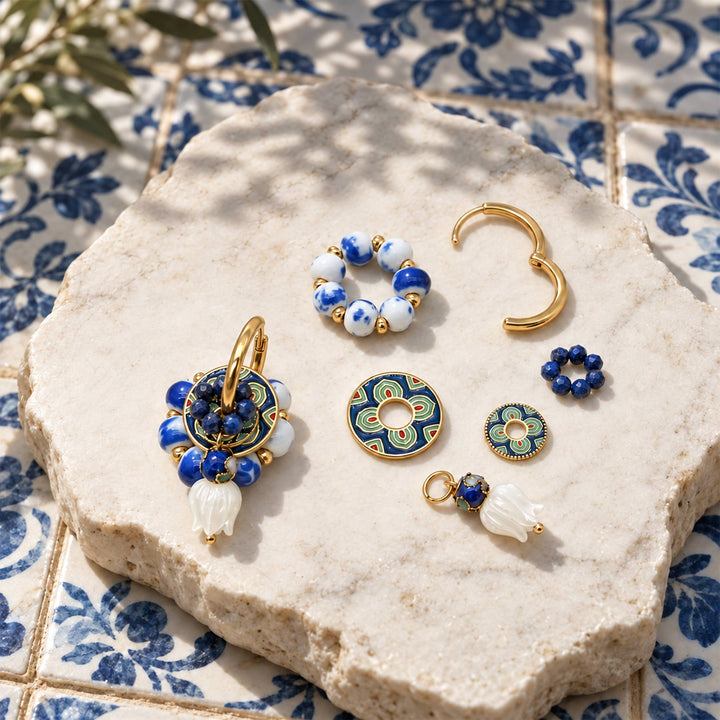 Convertible lapis hoop earrings with removable porcelain, enamel and mother-of-pearl components, arranged on a textured stone slab over blue and white patterned tiles.