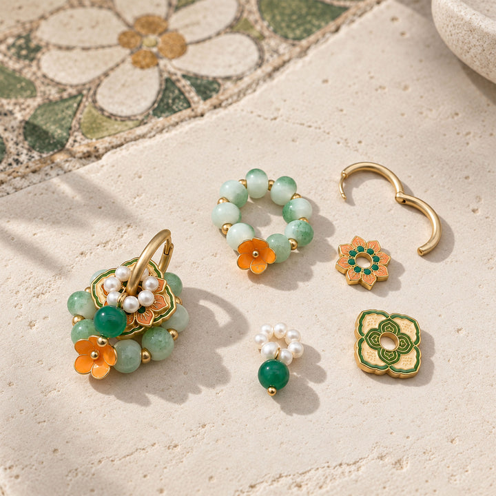 Green agate convertible hoop earrings with enamel flowers and porcelain beads arranged on a pale stone surface.