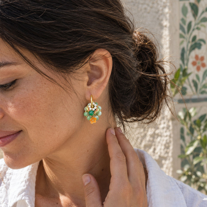 Model wearing green agate floral convertible hoop earrings outdoors against a pale stone wall.