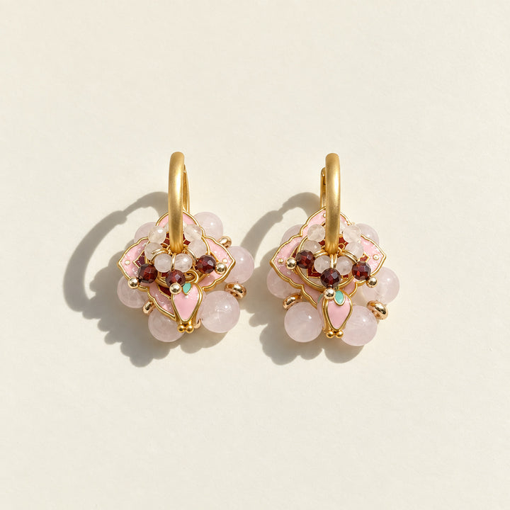 Pink quartz and garnet convertible hoop earrings with pink enamel details on a neutral sunlit background.