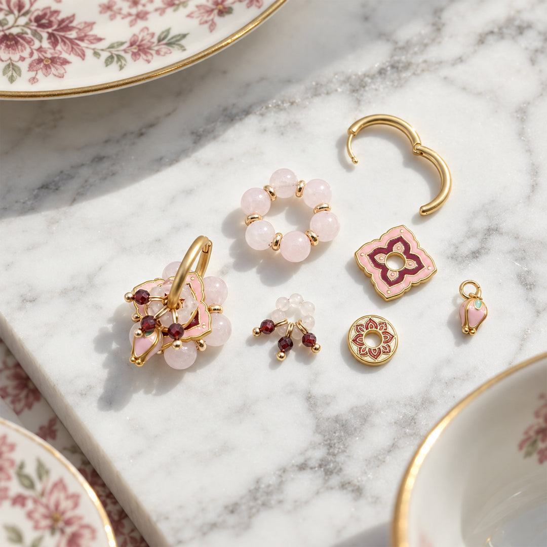 Pink quartz convertible earrings with removable garnet and enamel components arranged on a white marble slab.