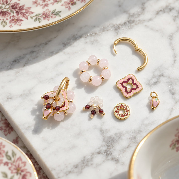 Pink quartz convertible earrings with removable garnet and enamel components arranged on a white marble slab.