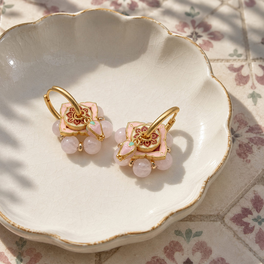 Pink quartz convertible hoop earrings with enamel charms displayed in a scalloped ceramic dish.