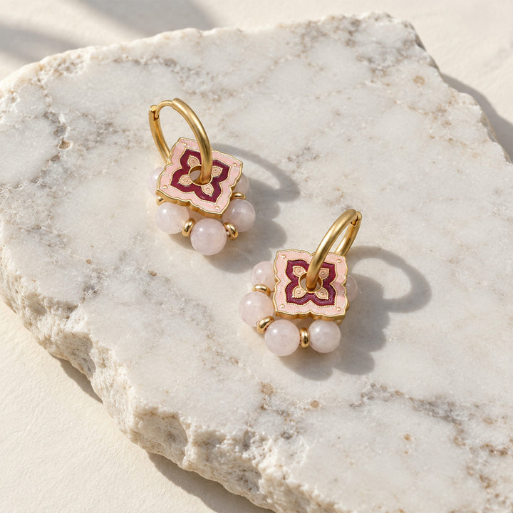 Pink quartz convertible hoop earrings with layered pink enamel details on a sunlit marble slab.