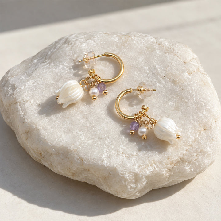 Convertible floral hoop earrings with mother-of-pearl Lily of the Valley drops and amethyst beads on pale stone.