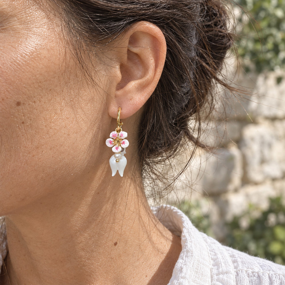 Model wearing Lily of the Valley convertible earrings with mother-of-pearl flowers and amethyst accents outdoors.