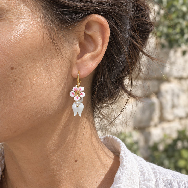 Model wearing Lily of the Valley convertible earrings with mother-of-pearl flowers and amethyst accents outdoors.