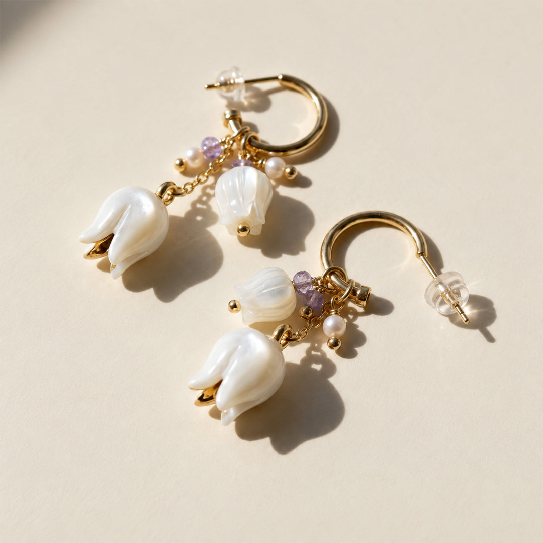 Mother-of-pearl Lily of the Valley convertible hoop earrings with amethyst and pearl details on a cream background.
