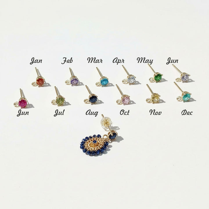 Custom birthstone earrings with interchangeable studs for each month shown beside gold and navy beaded dangle earring.
