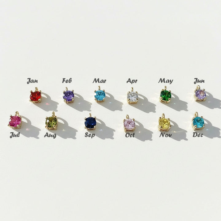 Row of gemstone pendants corresponding to each month on a light background