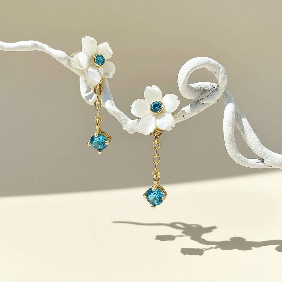 Floral earrings with blue gemstones on a beige background
