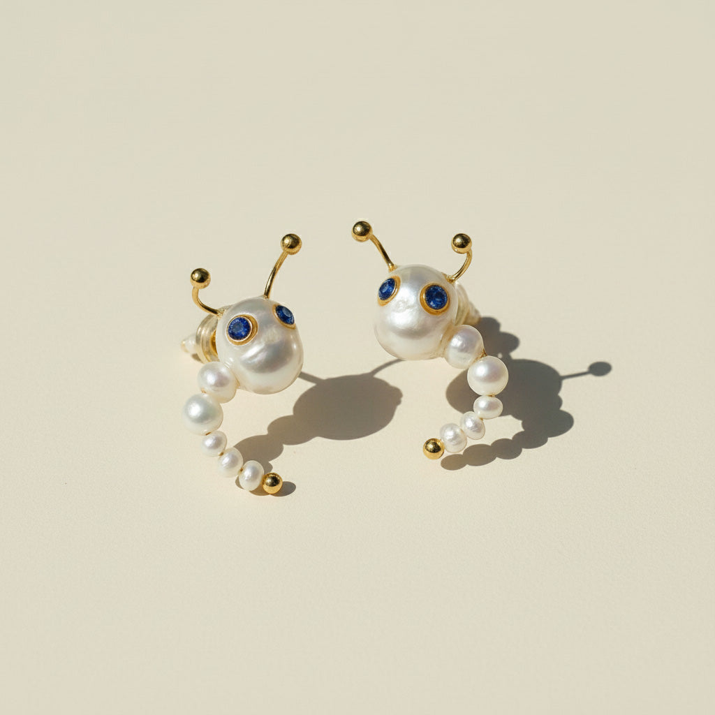 Pair of pearl earrings with gold accents on a beige background
