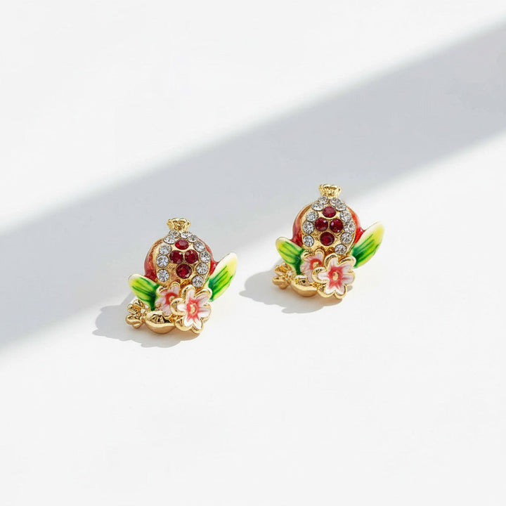 Artistic pomegranate enamel earrings under sunlight.