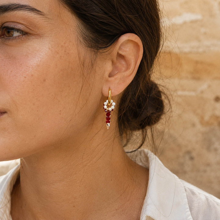 Woman wearing January Garnet convertible huggie earrings with freshwater pearl floral ring, garnet semi-precious stones and CZ glass birthstone charm.