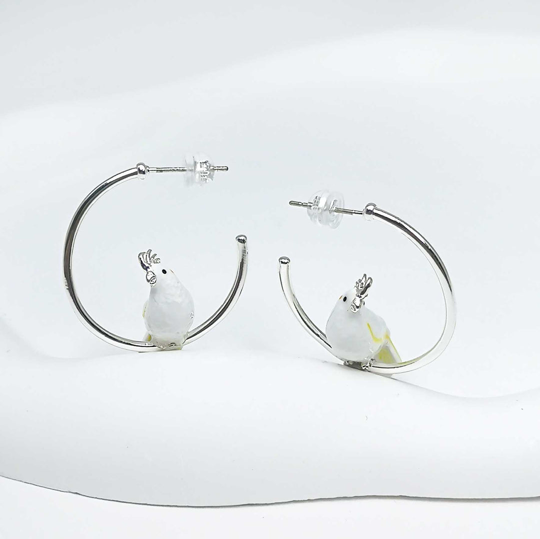 Hoop earrings with bird charms on a white background