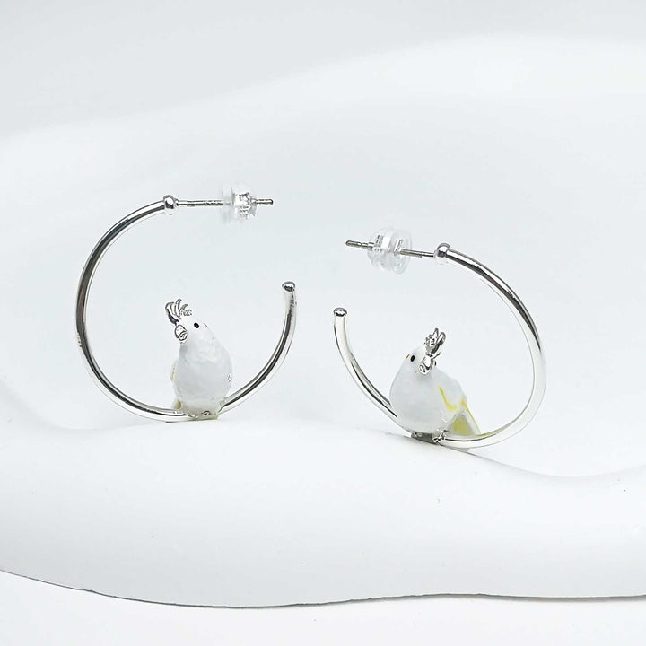 Hoop earrings with bird charms on a white background