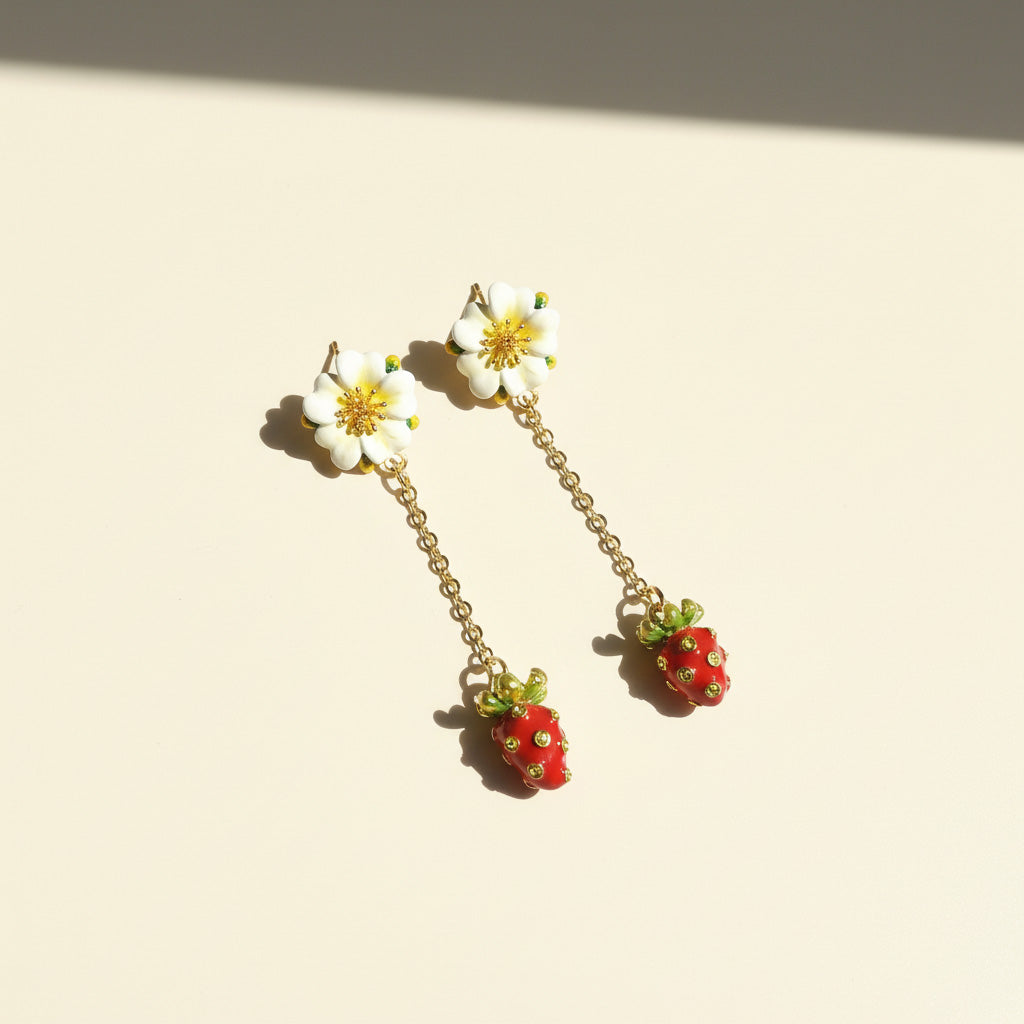 Floral and strawberry-themed earrings on a beige background