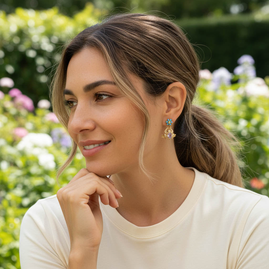 Close-up of mismatched frog earrings with colorful gemstones in garden setting.