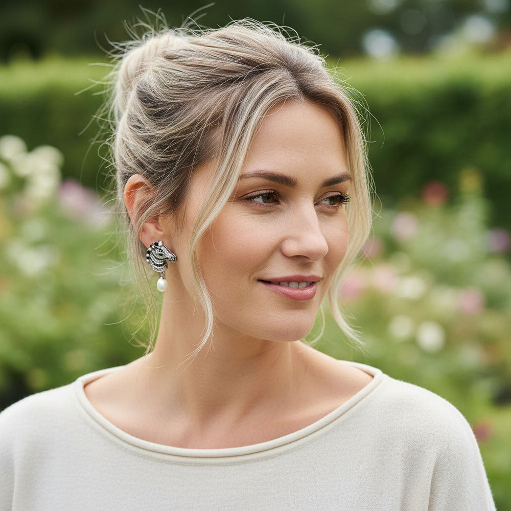 Woman with styled hair and earrings in a garden setting