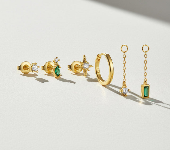 Gold jewelry set with emeralds on a light background