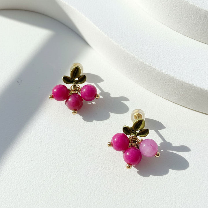 Pair of earrings with pink beads and gold accents on a white surface
