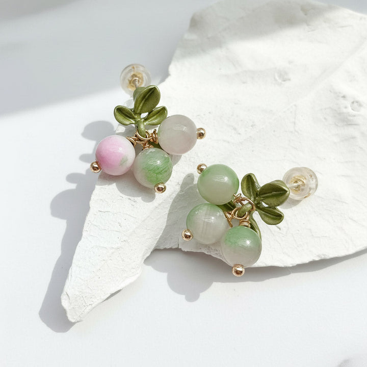 Earrings with green and pink beads on a white shell background