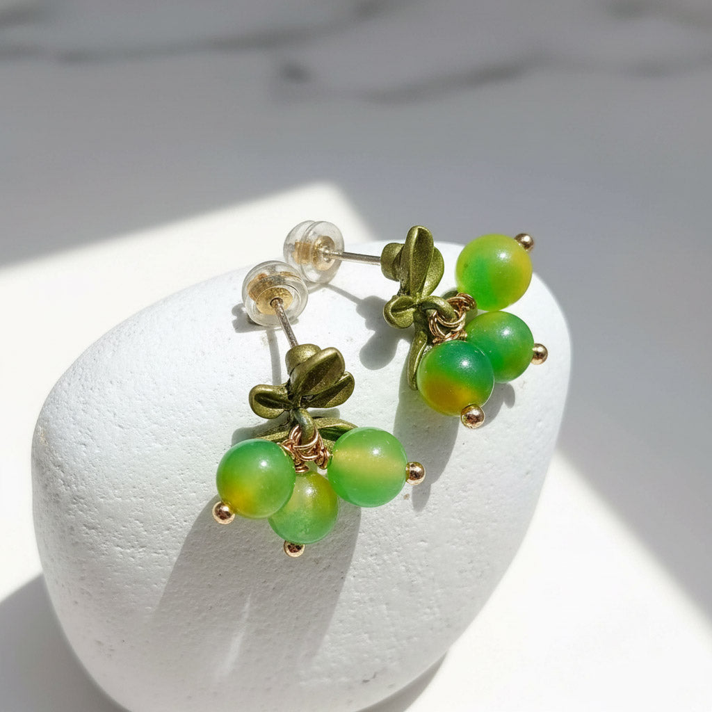 Green beaded earrings with gold accents on a white stone surface