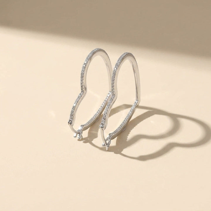 Silver hoop earrings with moissanite diamonds on a beige background