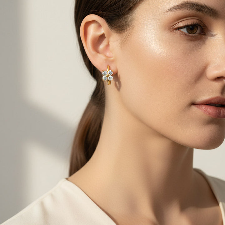 Gold floral huggie earrings with 3mm moissanite stones shown on model