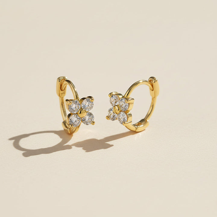 Close-up of gold moissanite floral huggie earrings with sparkling 3mm stones