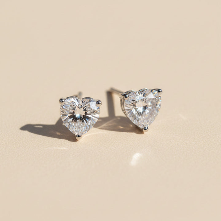 Heart-shaped 1ct lab diamond moissanite stud earrings on beige background