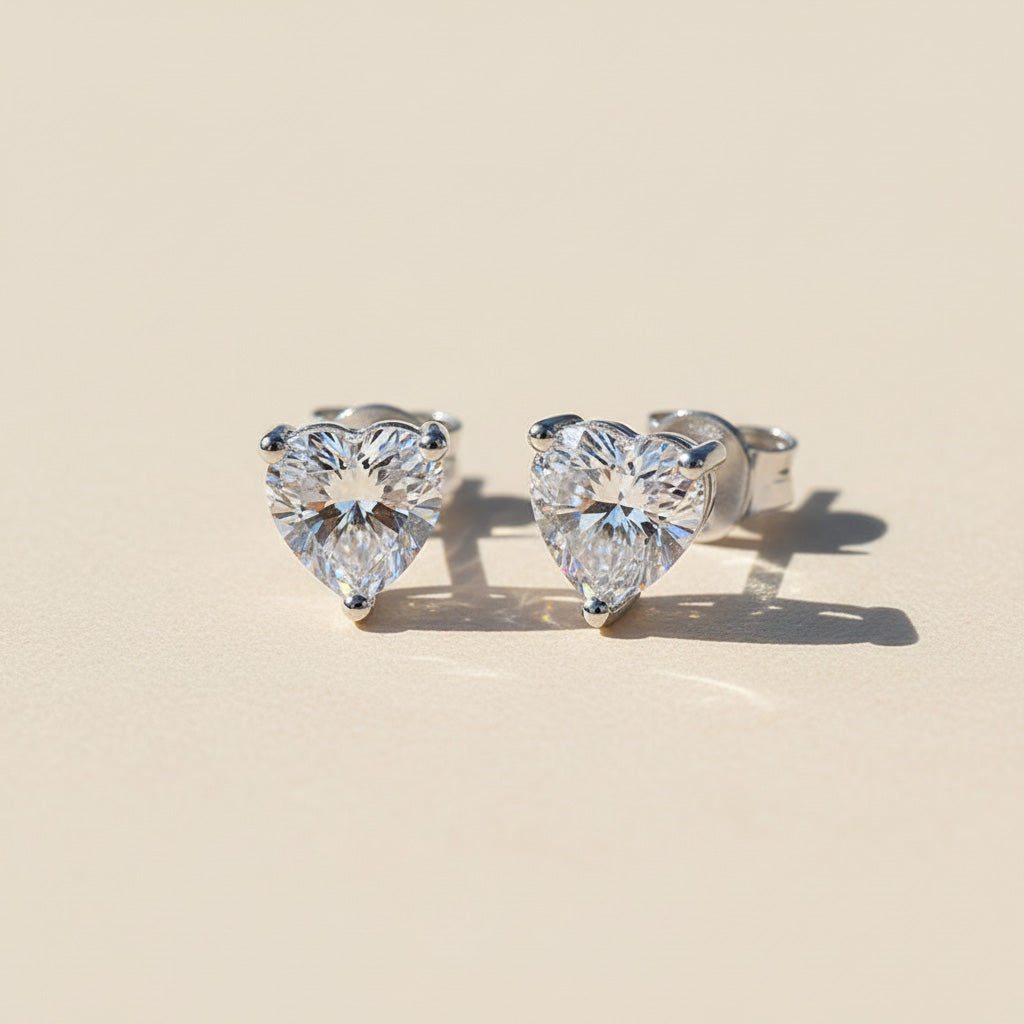 Pair of 1ct heart-cut moissanite earrings displayed on light surface
