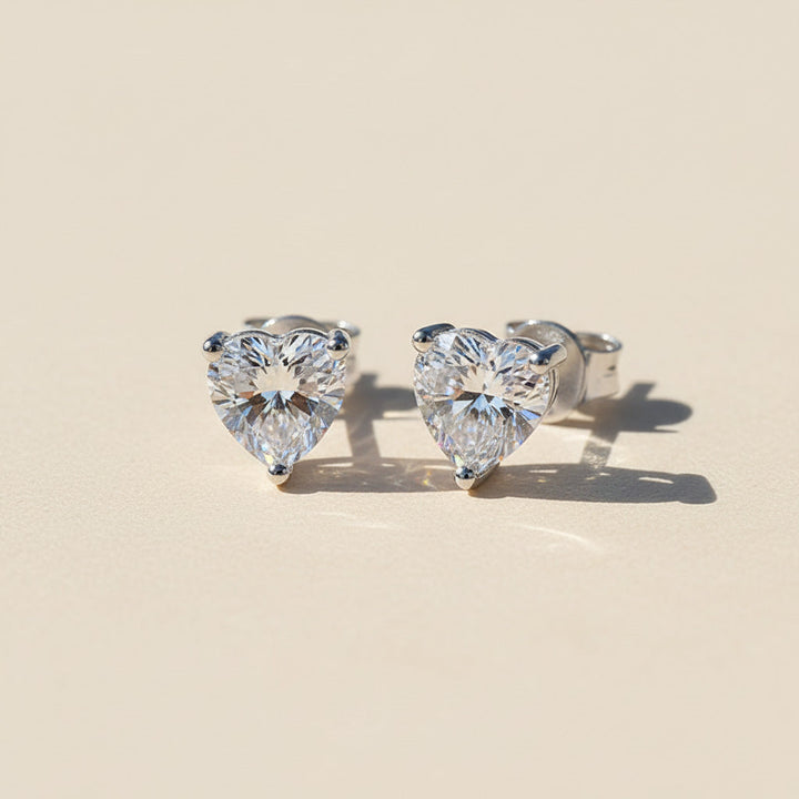 Pair of 1ct heart-cut moissanite earrings displayed on light surface
