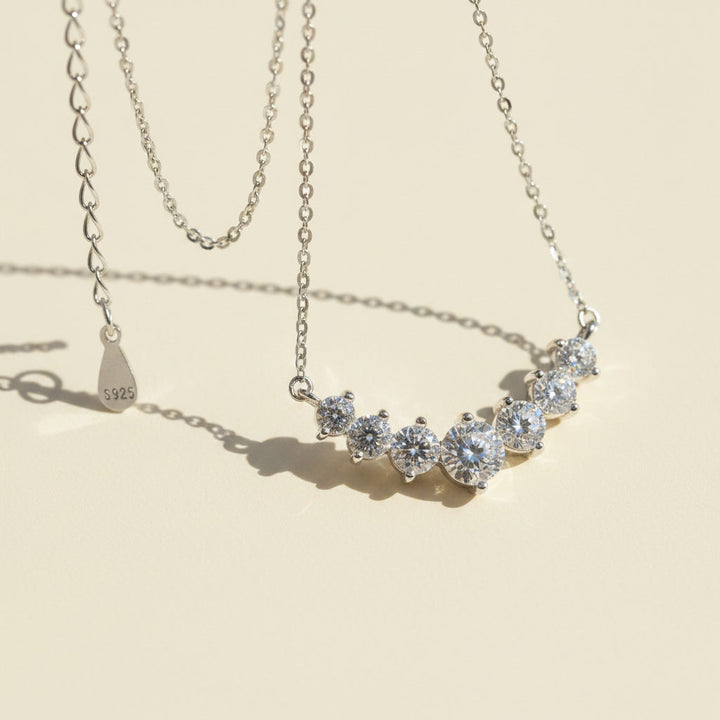 Silver necklace with moissanite diamond stones on a beige background