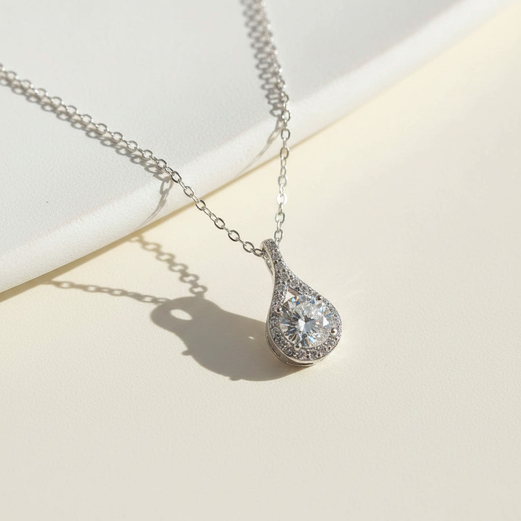 Silver teardrop necklace with a moissanite diamond pendant on a light background