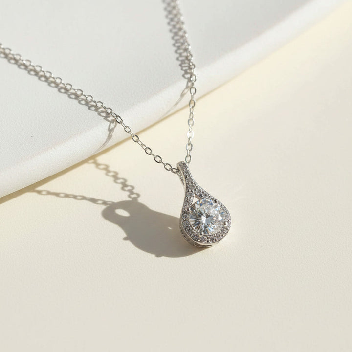 Silver teardrop necklace with a moissanite diamond pendant on a light background
