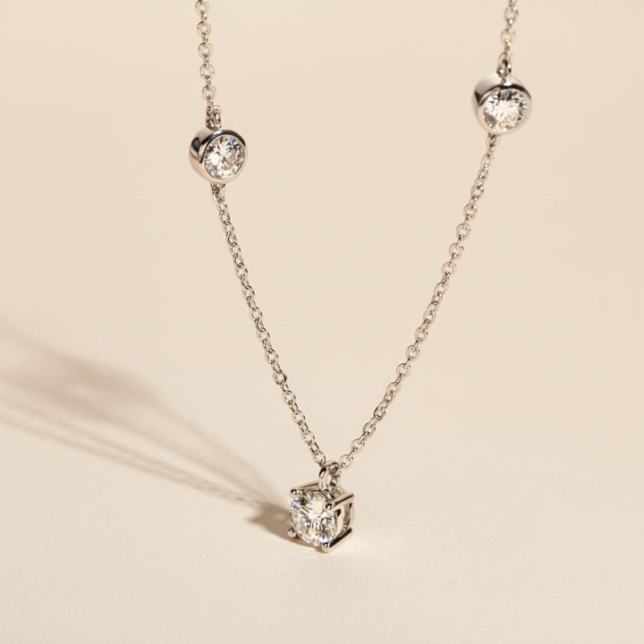 Moissanite cluster pendant necklace in platinum-plated silver shown in sunlight